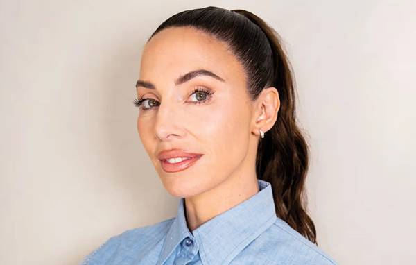Close-up of Whitney Cummings with a sleek high ponytail, wearing a light blue collared shirt