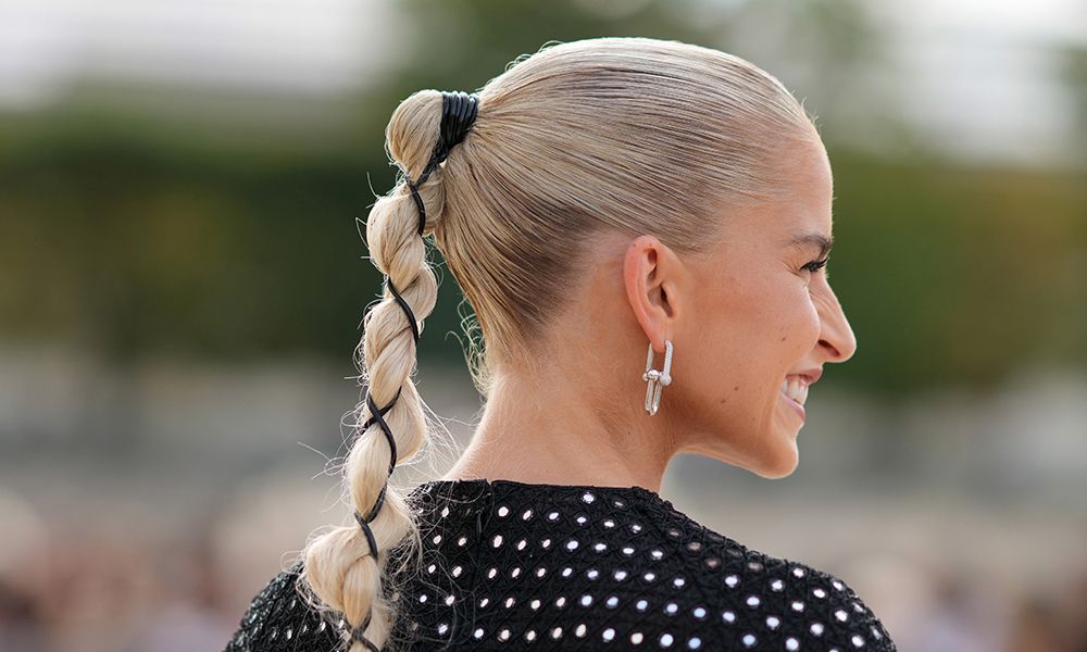 Caroline Daur wears earrings, a black and silver bejeweled shiny mini / short dress, bracelets, a pink bag outside Dior, during the Womenswear Spring/Summer 2024 as part of Paris Fashion Week on September 26, 2023 in Paris, France.