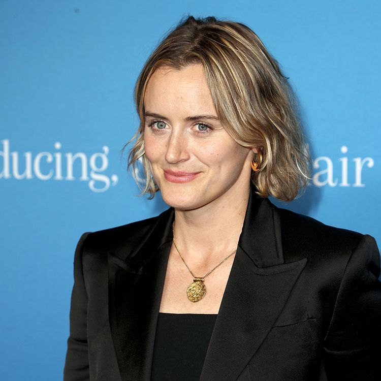 Taylor Schilling in a black suit in front of a blue background