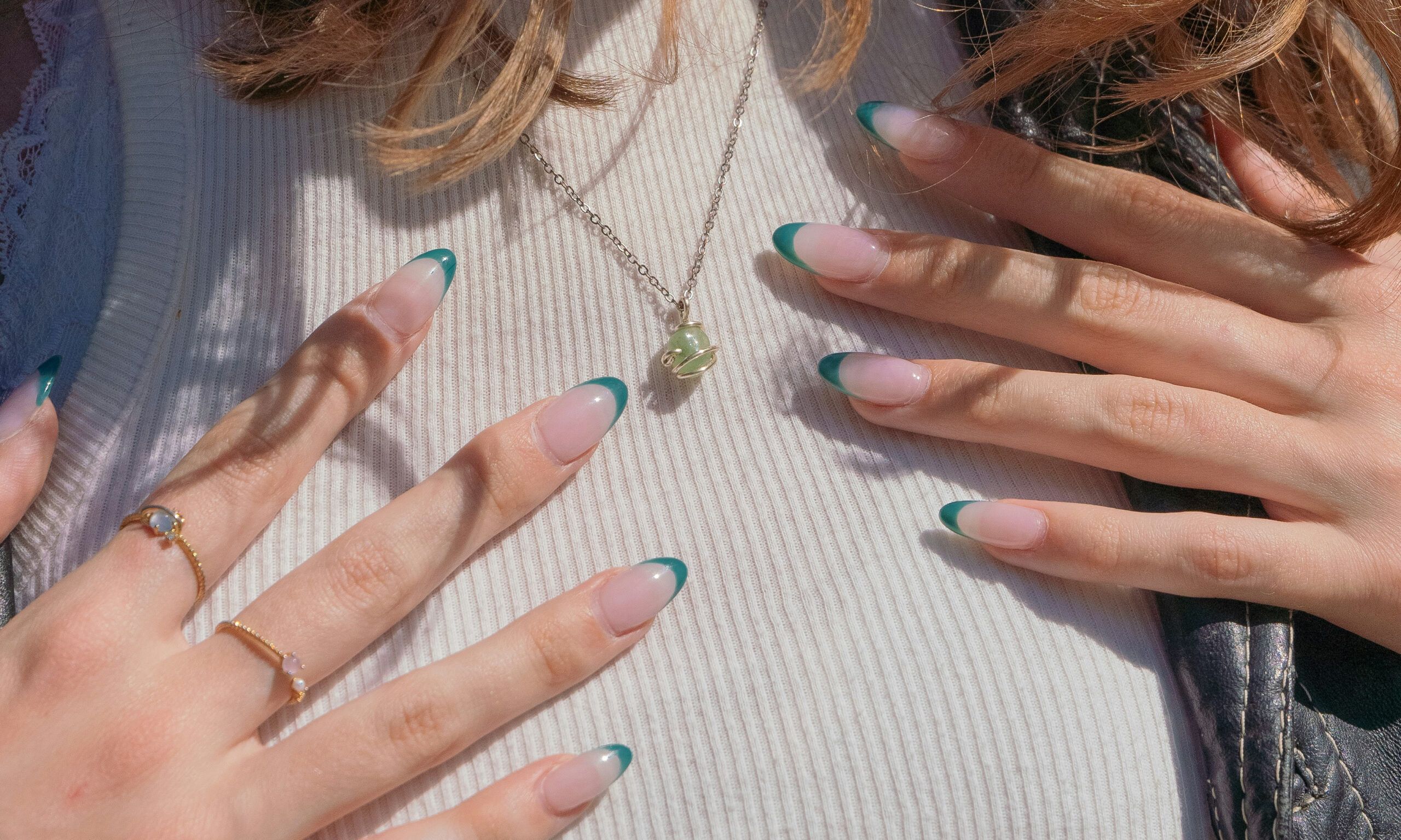 close up of manicured hands with green nail tips on woman's chest