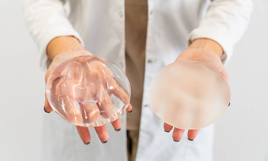 The Doctor's hands holding two different types of breast prostheses.
