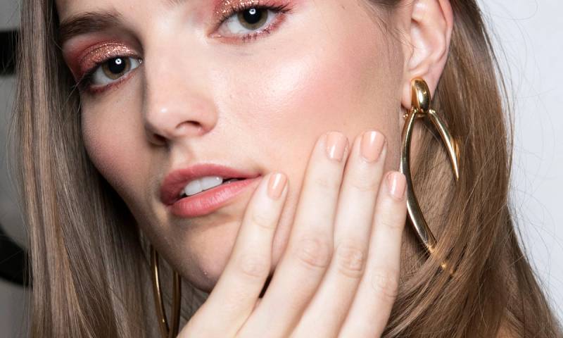 model with nude nail polish manicure touching her cheek