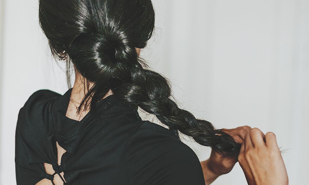 rear view young latina doing baraided hair at home