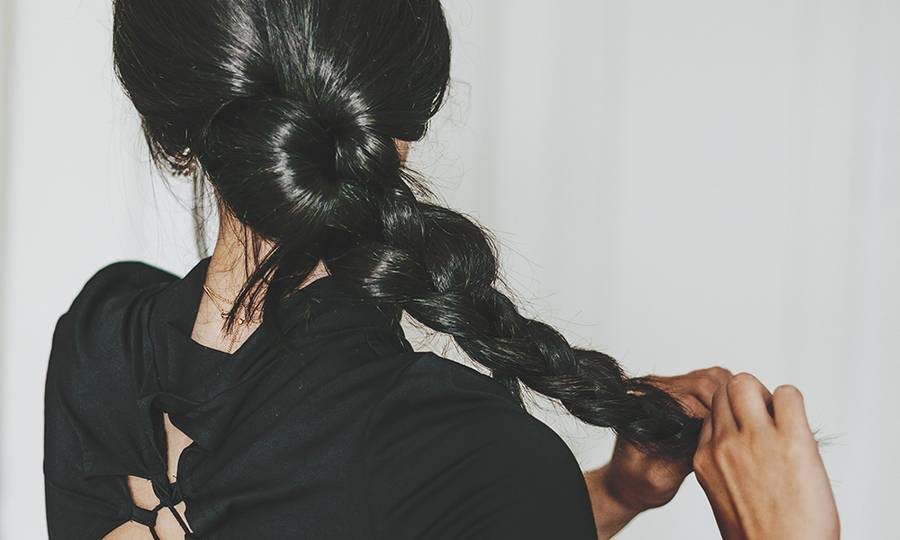 rear view young latina doing baraided hair at home
