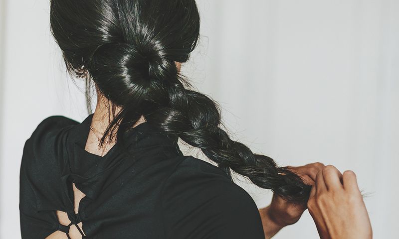 rear view young latina doing baraided hair at home