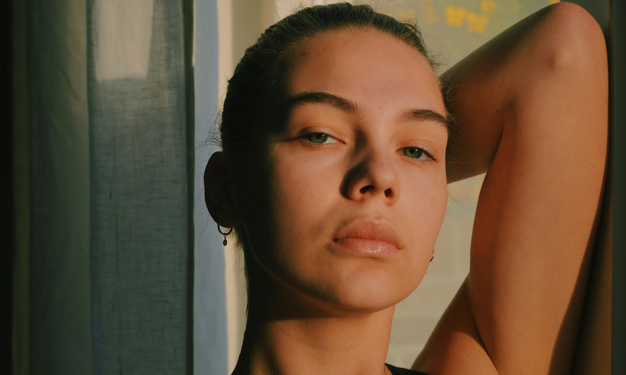 woman with arm up over her head in low sunlight