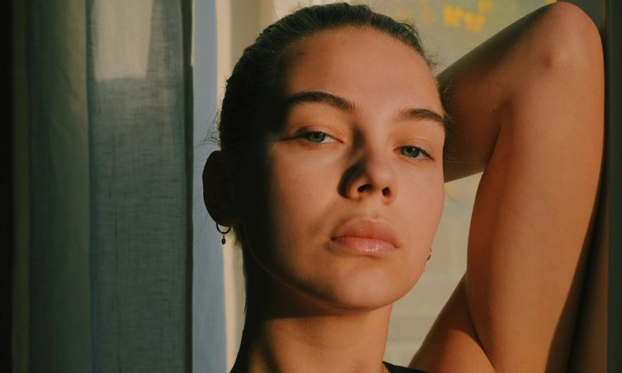 woman with arm up over her head in low sunlight
