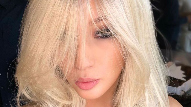 A close up of a woman's face with feathery, full hair and her bangs cascading by eyes