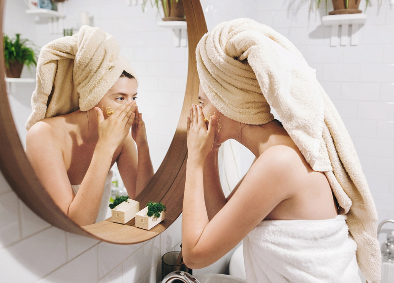woman in towel looking in mirror