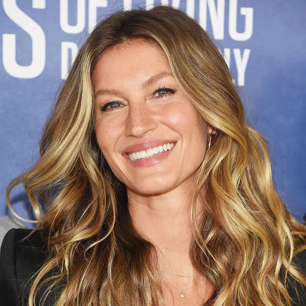 Gisele Bundchen with eavy blonde hair posing in front of blue background