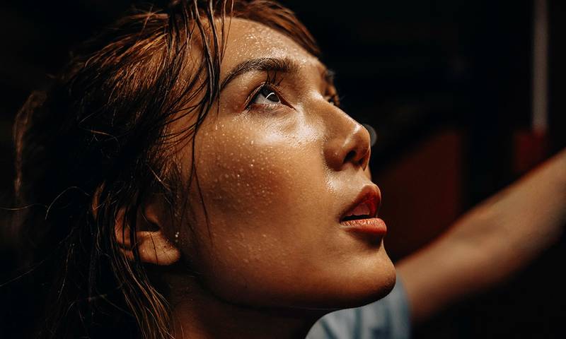 Face of female athlete with sweat while working out at gym
