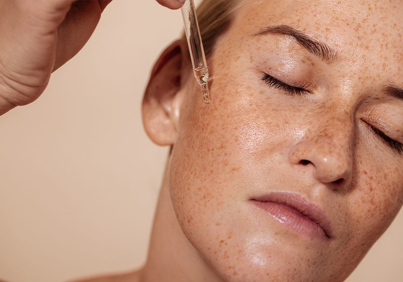 woman putting serum on face
