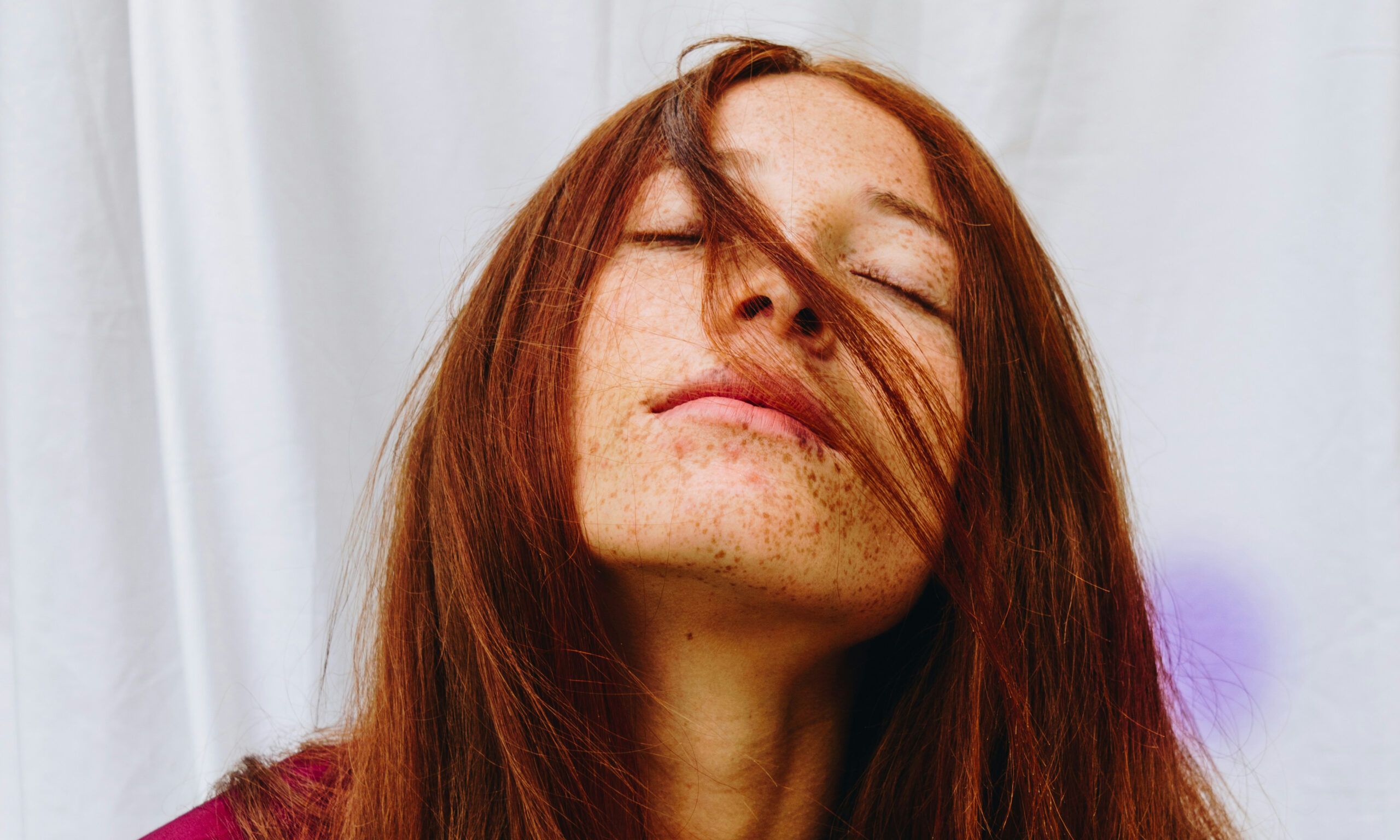 woman with red straight hair with eyes closed