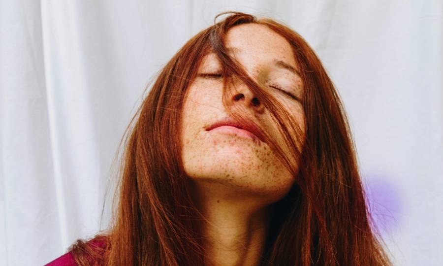 woman with red straight hair with eyes closed