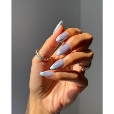 A close up of a woman's hand with her manicured nails and rings on multiple fingers