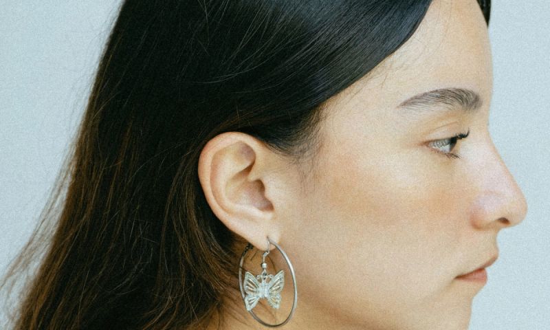 Side view of woman with brown hair tucked behind ear