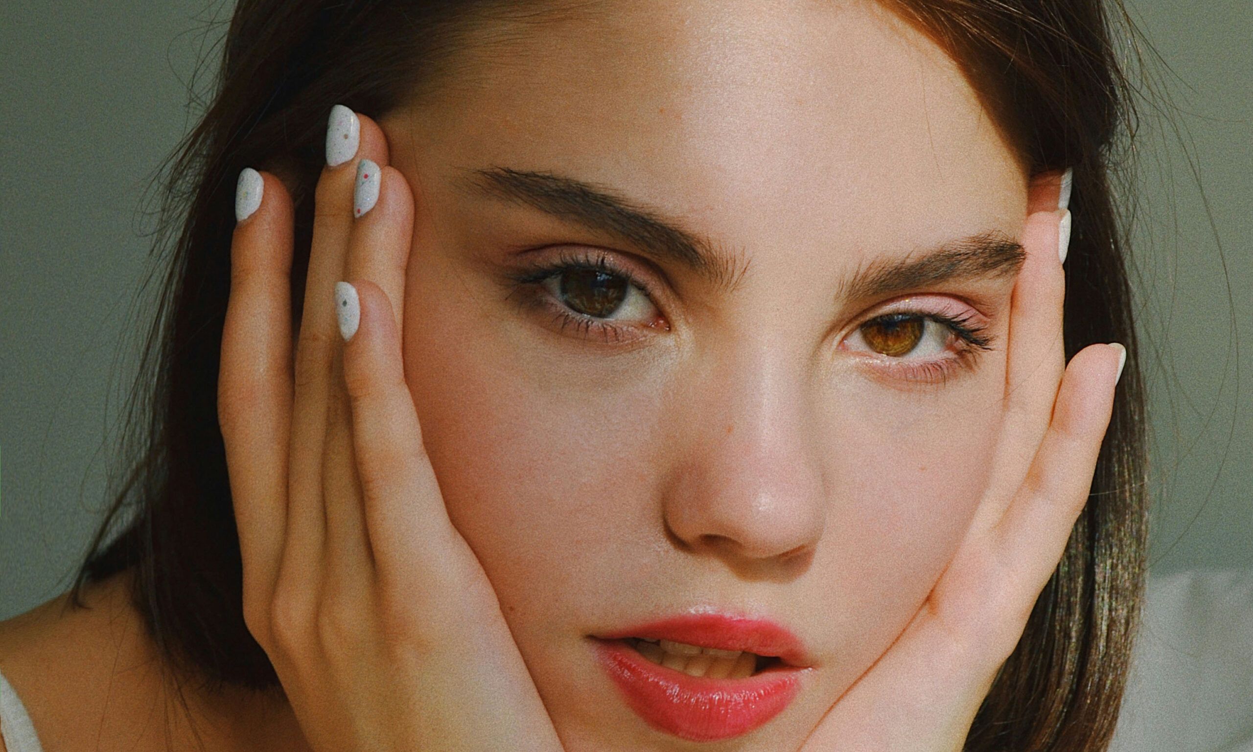 close up view of young woman with hands on her face