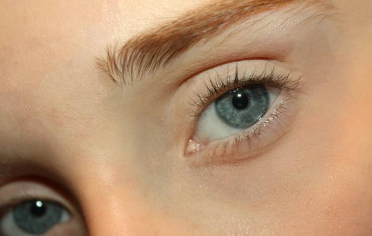 Close-up of a light-eyed woman with soft auburn brows that blend naturally with her fair skin tone, illustrating a low-contrast look.