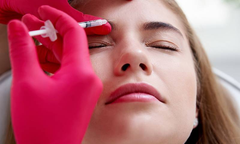 Beauty injections into a young female face. Smoothing of mimic wrinkles using biorevitalization