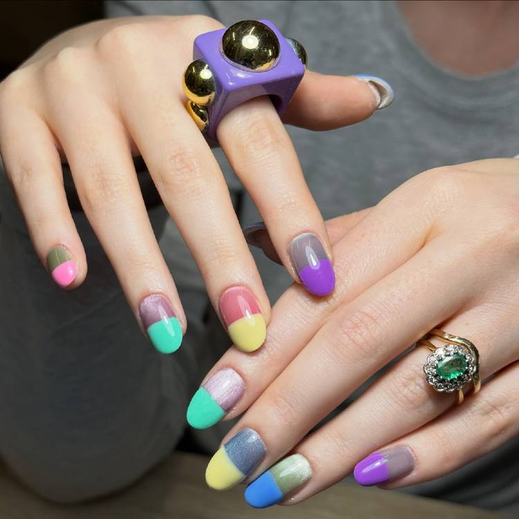 Hands with glossy pill-box-inspired color-block nails in pastel yellow, mint, purple, blue and pink shades with bold statement rings.