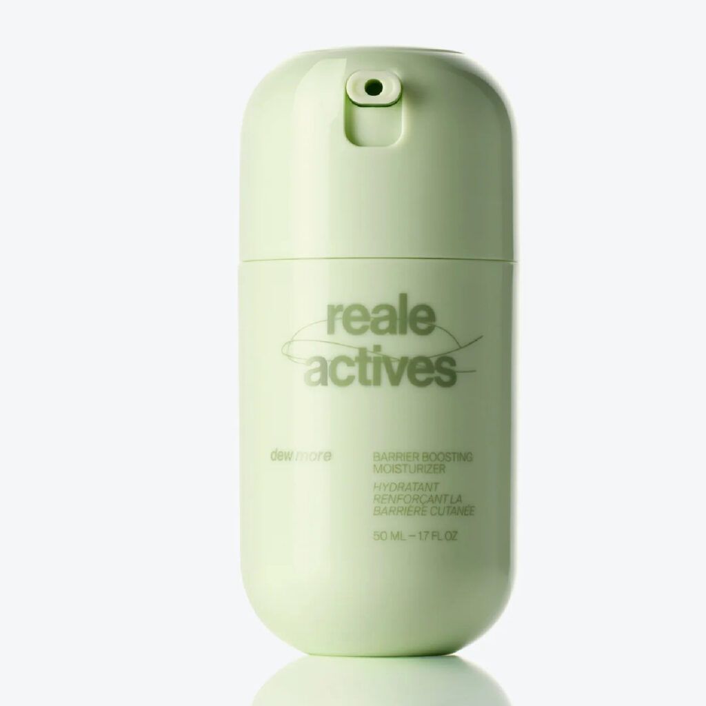 Reale Actives Dew More Barrier-Boosting Moisturizer in a sleek, reflective chrome bottle with pale green branding, shown on a glossy surface against a clean white background.