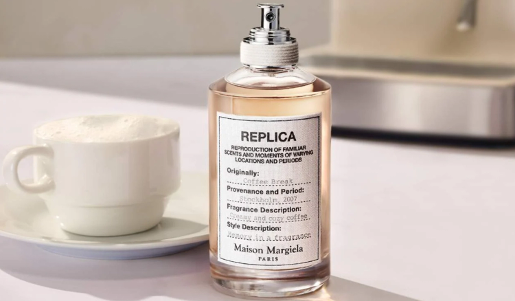 Maison Margiela Replica Coffee Break fragrance bottle beside a white coffee cup and saucer.