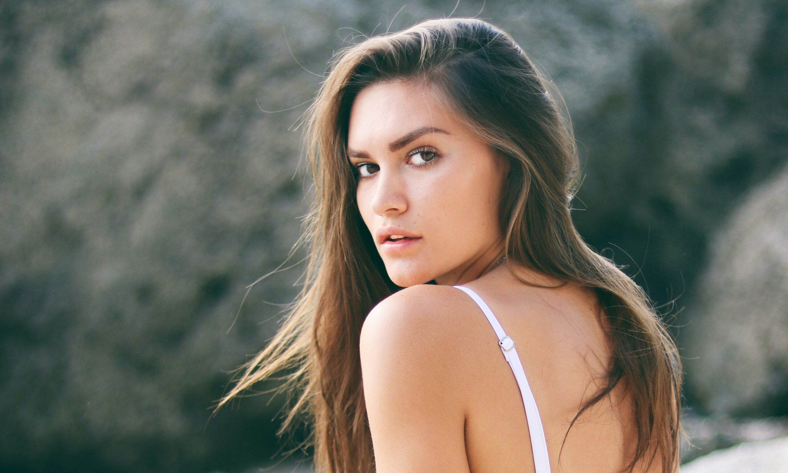 Woman kneeling on the beach looking over shoulder