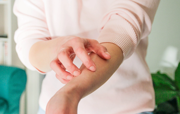 Close-up of a person scratching their forearm with their fingers