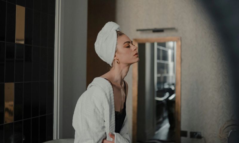 side profile of woman in robe with towel on her head