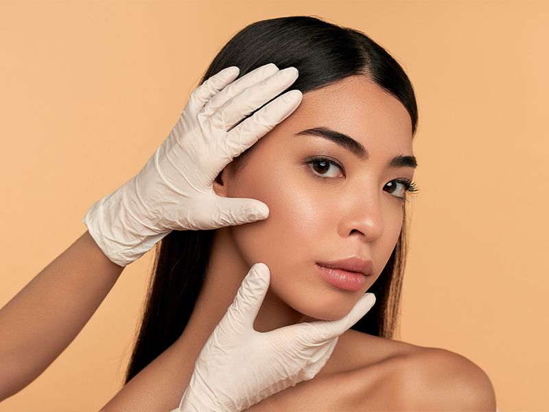 gloved hands on woman's face