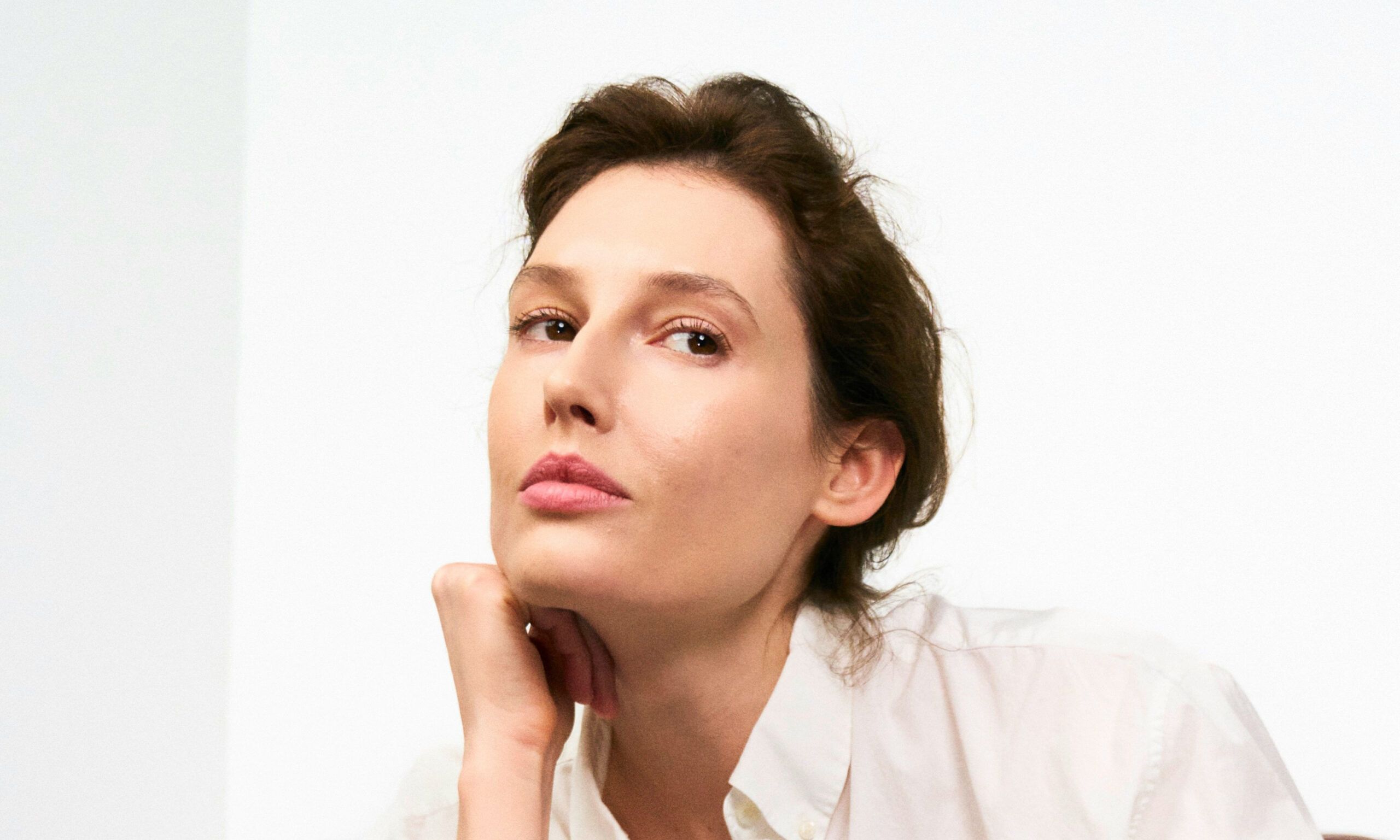 older woman in white blouse with hands on her chin
