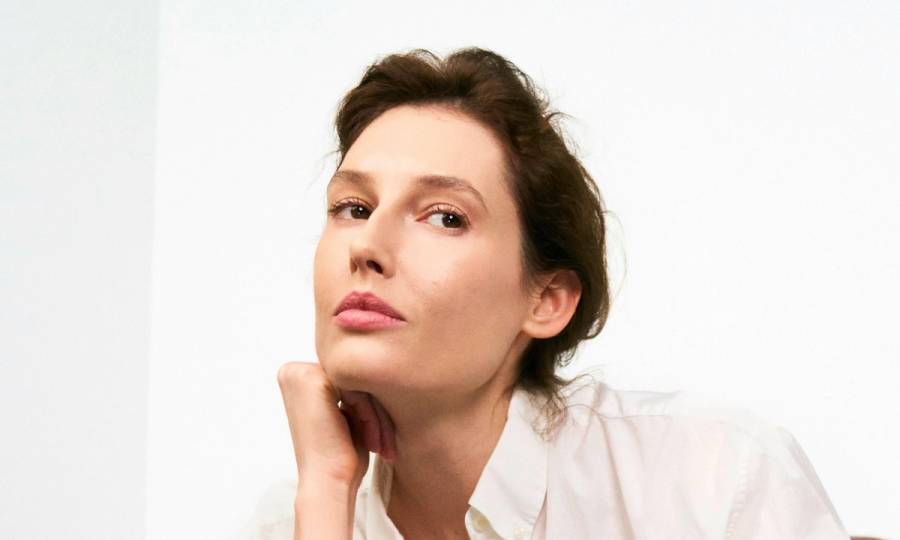 older woman in white blouse with hands on her chin