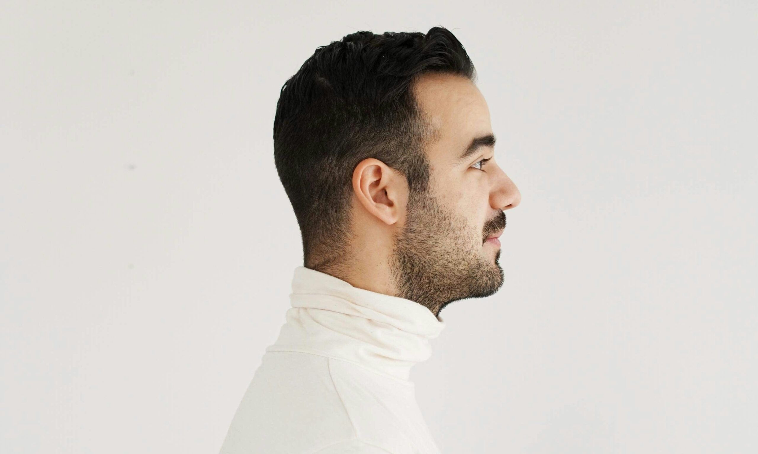 side profile of man in a white turtleneck