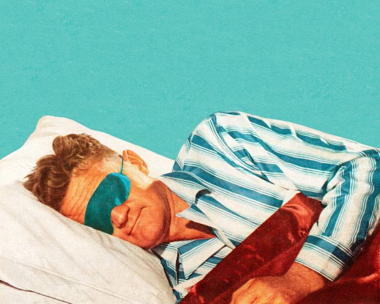 Person wearing a teal sleep mask and striped pajamas lies on their side on a white pillow beneath a red blanket.