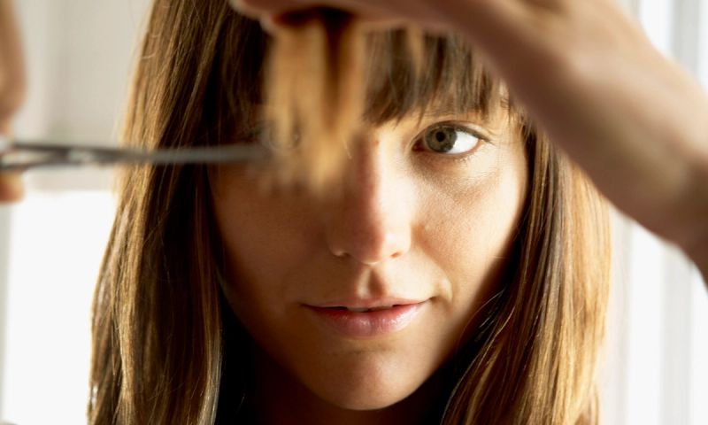 Woman cutting hair with scissors