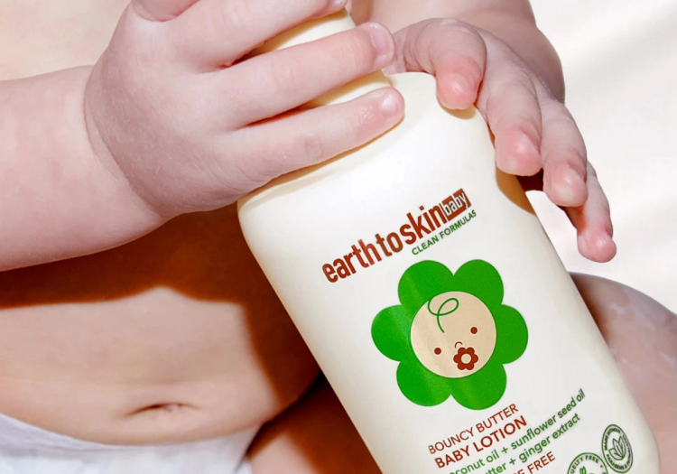 A baby's hands hold a bottle of Earth to Skin Baby Bouncy Butter Baby Lotion