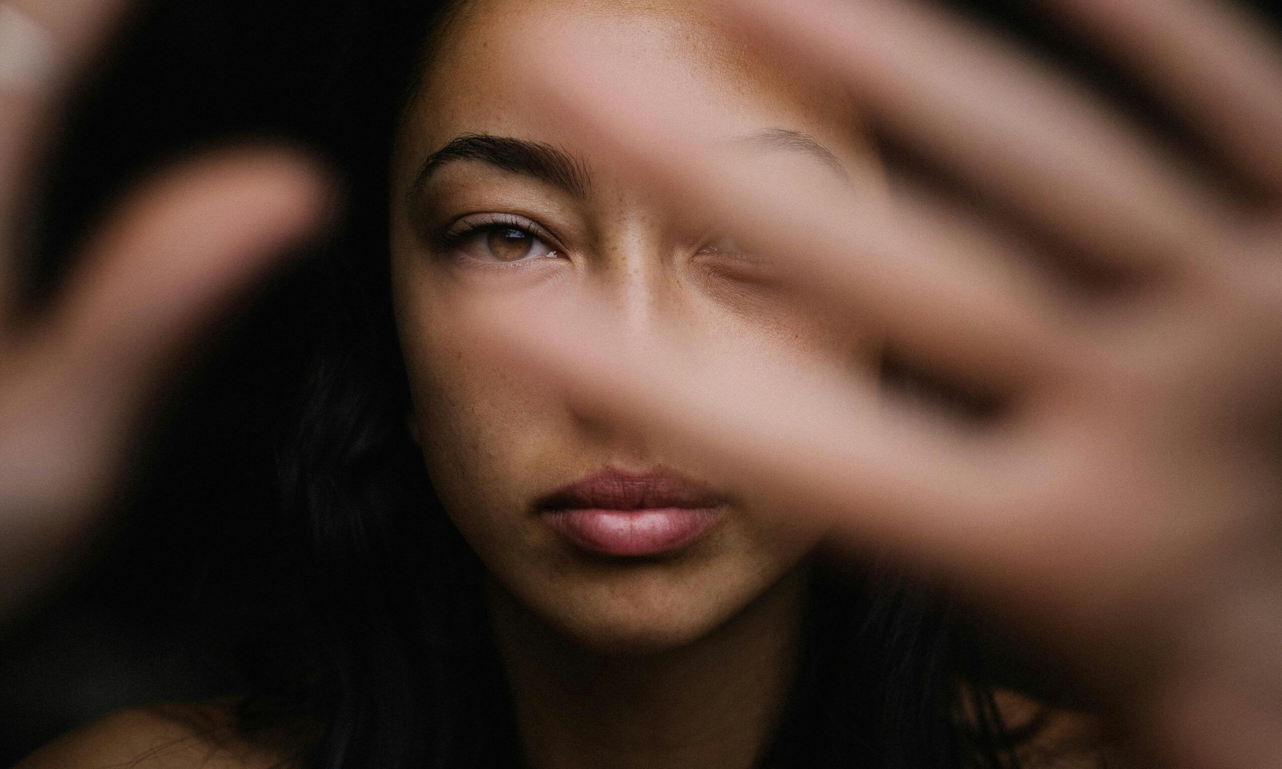 woman in dark with hands at camera