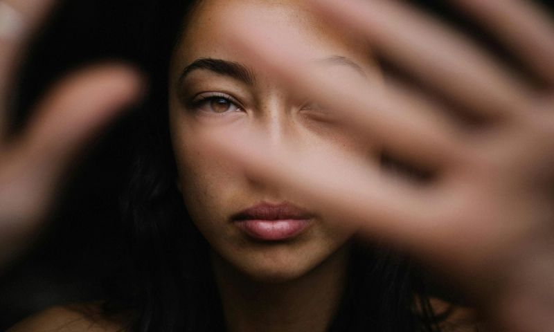 woman in dark with hands at camera