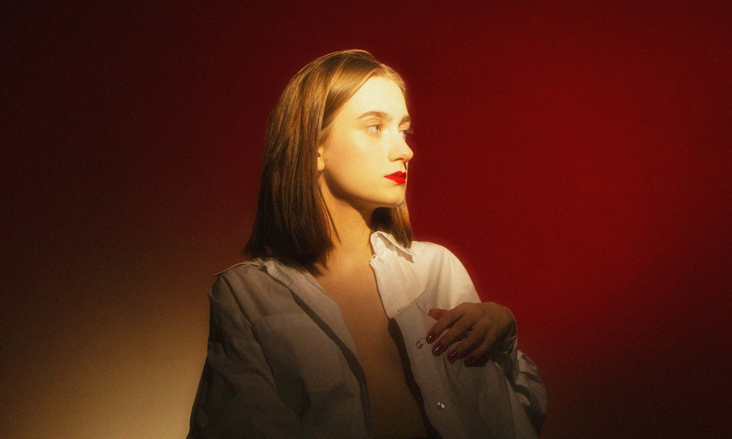 model looking to the side in golden light against a red background