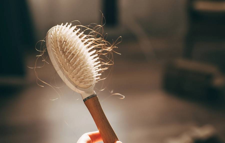 A woman holds a wooden comb in her hands, cleans it of fallen hair after combing