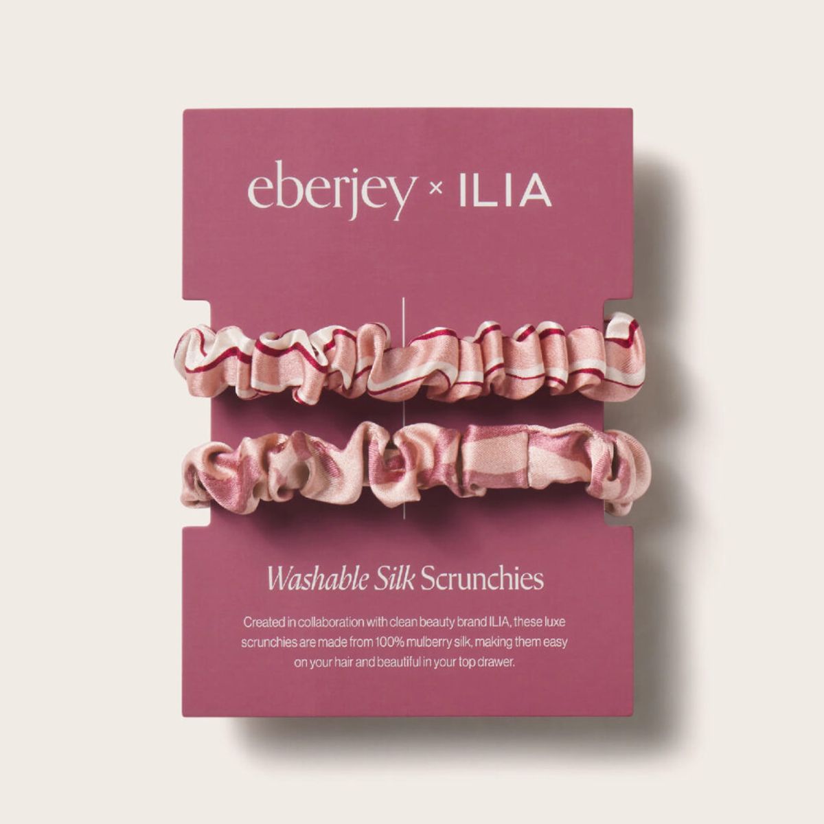 Eberjey x ILIA washable silk scrunchies in pink stripe and palm prints displayed on branded packaging from the Silk Rituals collection.