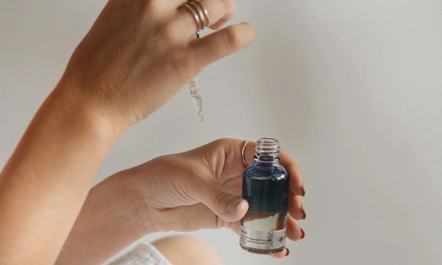 close up of woman putting skin serum on her hand