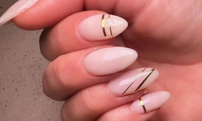 close up of gel manicure with nude nail polish and gold nail art
