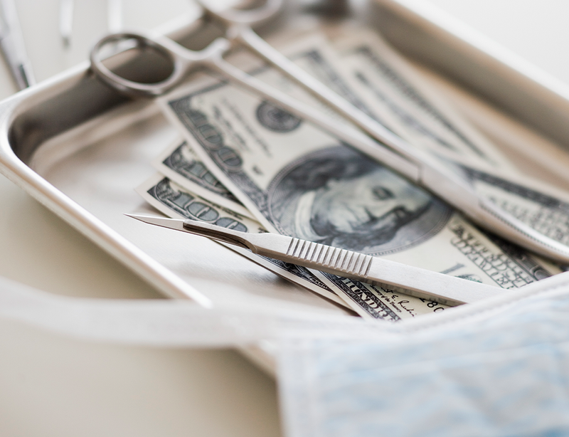 money and surgical tools on medical tray