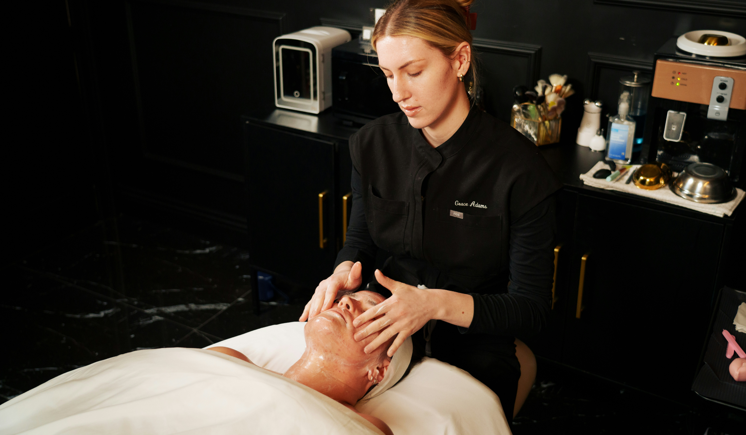 Aesthetician massaging a client’s face during a facial treatment in a spa.
