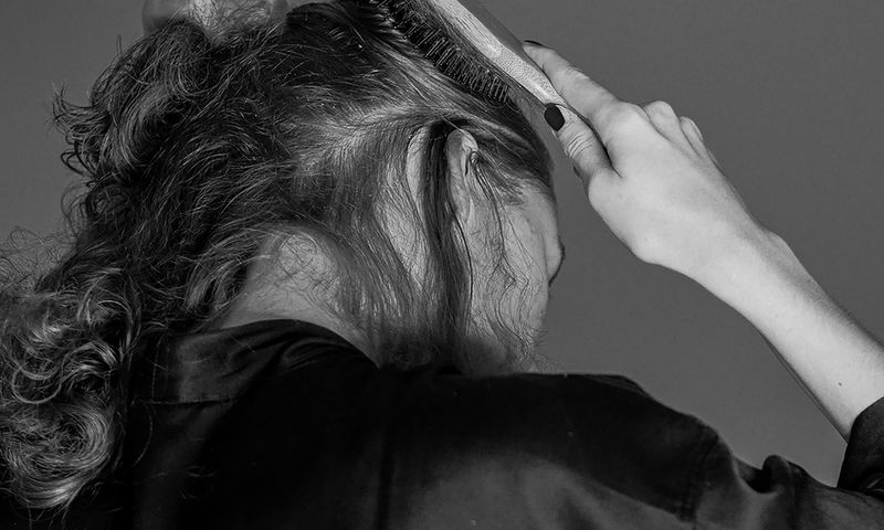 black and white photo of back view of woman brushing hair