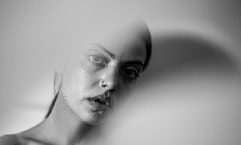 black and white photo of woman's face behind shadows