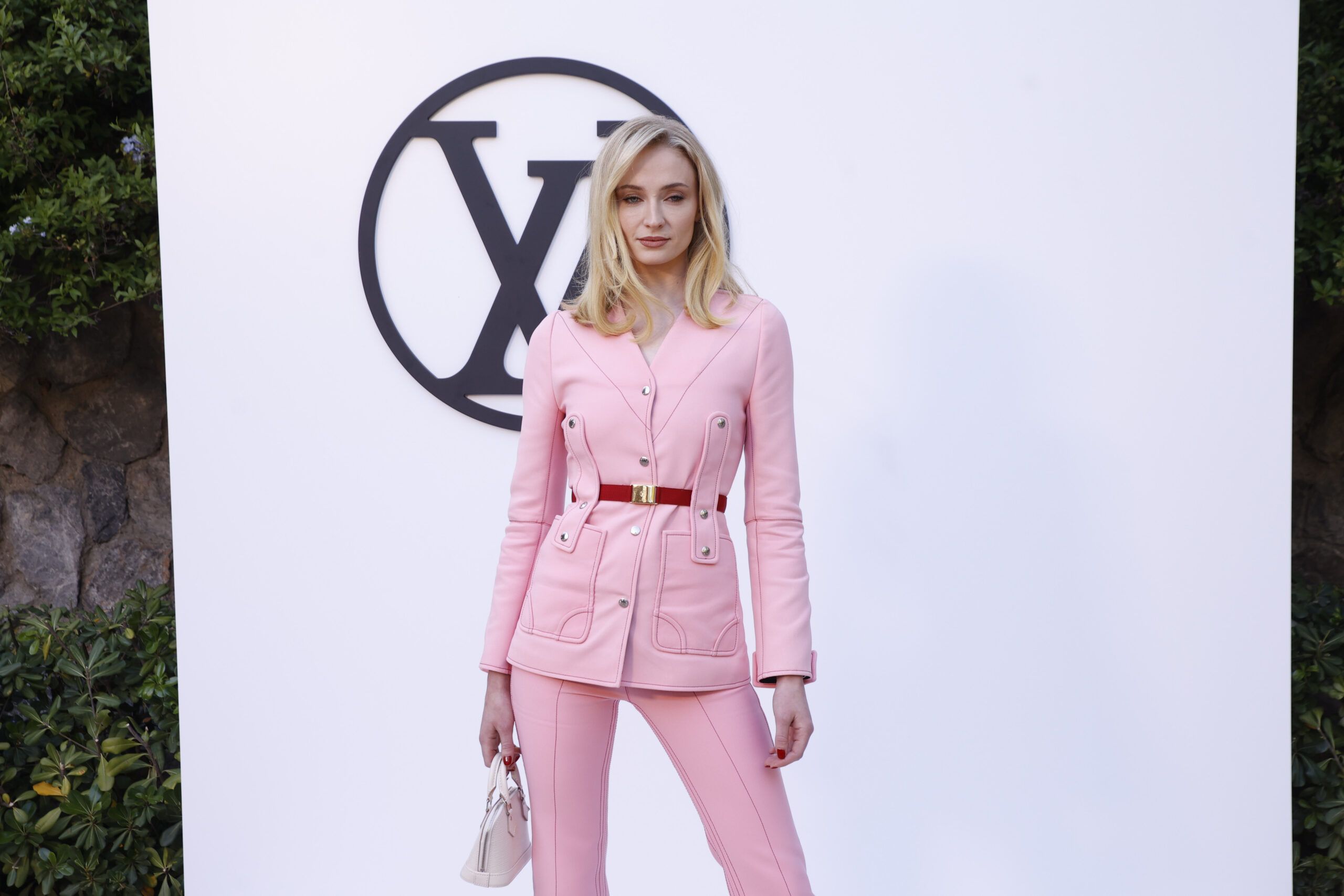 Sophie Turner with blonde hair wearing a pink two-piece suit