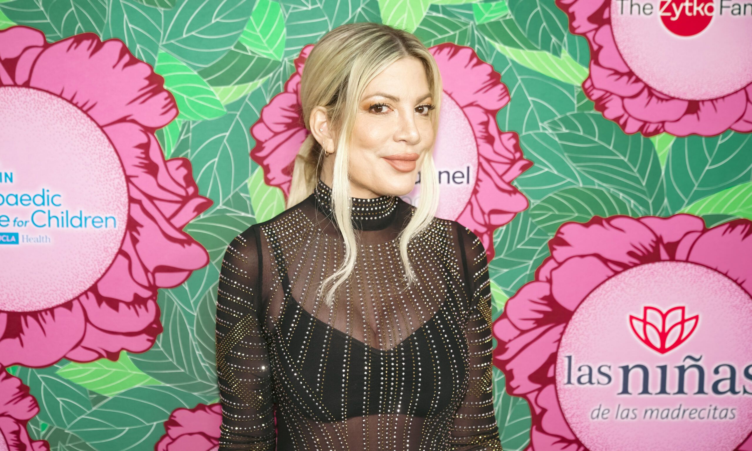 Tori Spelling posing in front of a colorful background