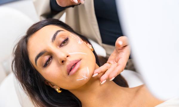 Woman with correcting lines painted on the face in a beautician clinic